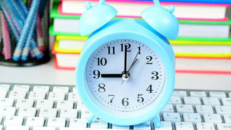 Time management concept image with clock, keyboard and books in the background